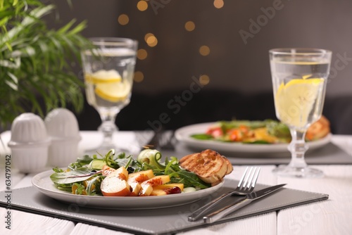 Delicious salad with peach slices served on white wooden table