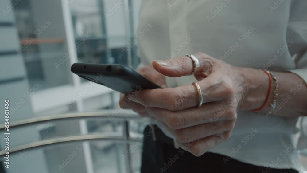 Close up of female hands of office worker using smartphone while going up in elevator in modern business center Close up of female hands of office worker using smartphone while going up in elevator in modern business center