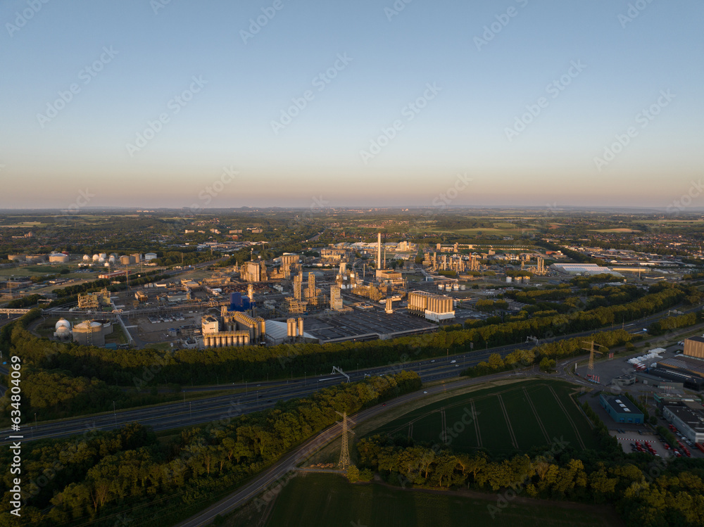 Aerial drone view of chemical industrial park at Geleen with a large cooling tower at sunset.