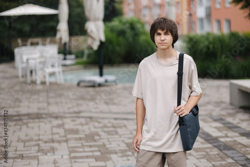 Portrait of teenage boy student with laptop bag go home after college © Aleksandr