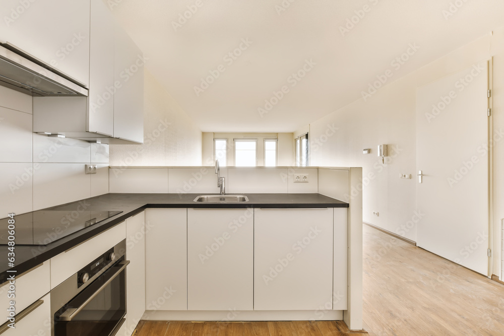 an empty kitchen with white cabinets and black counter tops on the island in front of the sink is also visible an empty kitchen with white cabinets and black counter tops on the island in front of the sink is also visible
