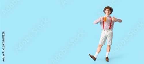 German man with beer showing thumb-up on light blue background with space for text. Banner for Octoberfest