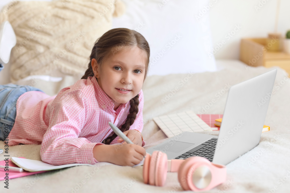 Little girl with laptop studying computer sciences online in bedroom Little girl with laptop studying computer sciences online in bedroom