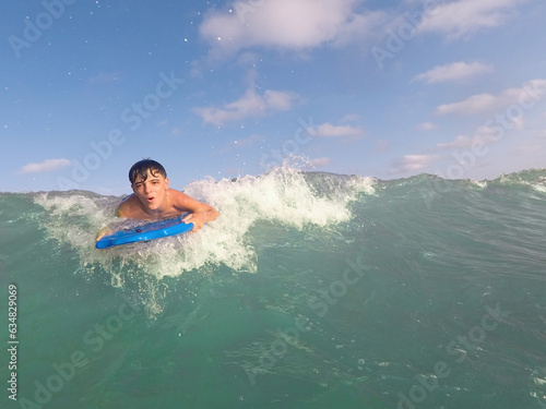 boy bodyboarding a wave on a turquoise water beach on a sunny summer day, bodysurfing, fun at the beach, copy space