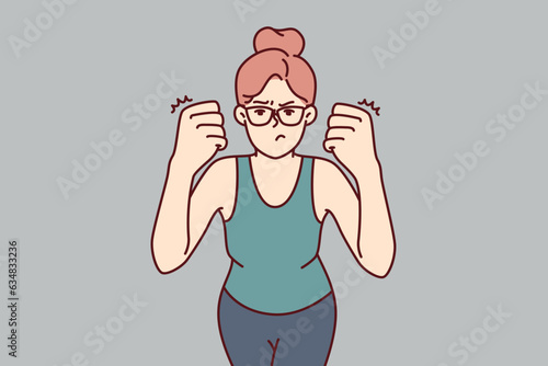 Woman clenches fists demonstrating willingness to fight and feeling desire to beat offender because of insult or aggression. Strong girl in glasses looks at screen showing aggression and hatred