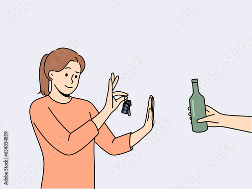 Woman driver refuses alcohol and holds car keys standing near human hand with bottle of beer. Concept of sobriety and awareness of driver who does not want to drive after drinking alcohol