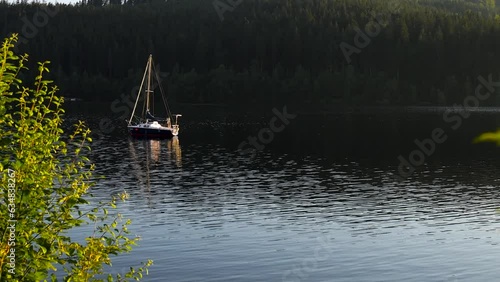 Sailboat on a mountain lake in summer at sunset photo