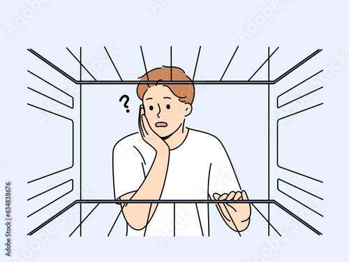 Hungry man sees empty refrigerator and is nervous about lack food due to poverty and financial crisis. Young embarrassed guy looks into refrigerator compartment surprised by lack products on shelves