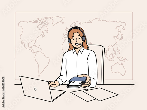 Woman manager of travel agency sits at office desk and holds passport with visas and plane tickets. Tour operator company representative in headphones near giant map of world helps to travel