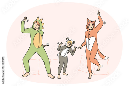 People in kigurumi pajamas have fun dancing indoors. Smiling adults and kid enjoying pyjama home party together. Leisure weekend. Vector illustration.