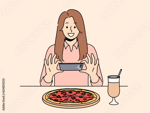 Woman takes picture of pizza on phone, wanting to make post on social network and talk about life. Girl blogger take shot of pizza while visiting restaurant of traditional italian cuisine