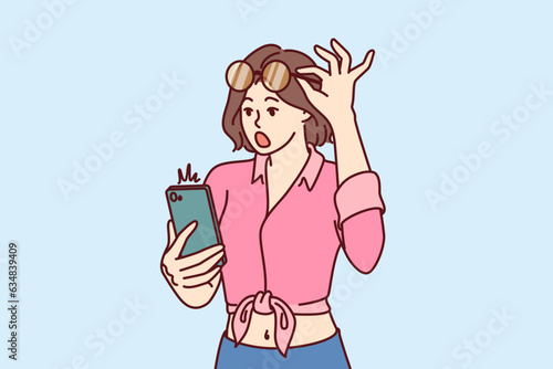 Shocked woman with mobile phone raises glasses and opens mouth after reading amazing news on internet. Young shocked girl received SMS in smartphone about storm warning or AMBER alert
