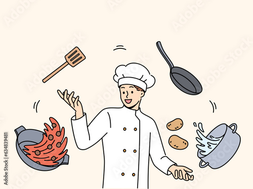 Man cook in white uniform and cap stands among flying pots and ingredients for cooking delicious soup. Professional guy cafe cook comes up with recipe for new dish for restaurant menu