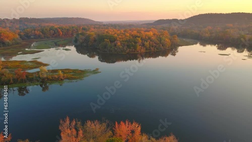 Sunrise drone long shot over colorful still lake water reflection during fall with autumn colored trees photo