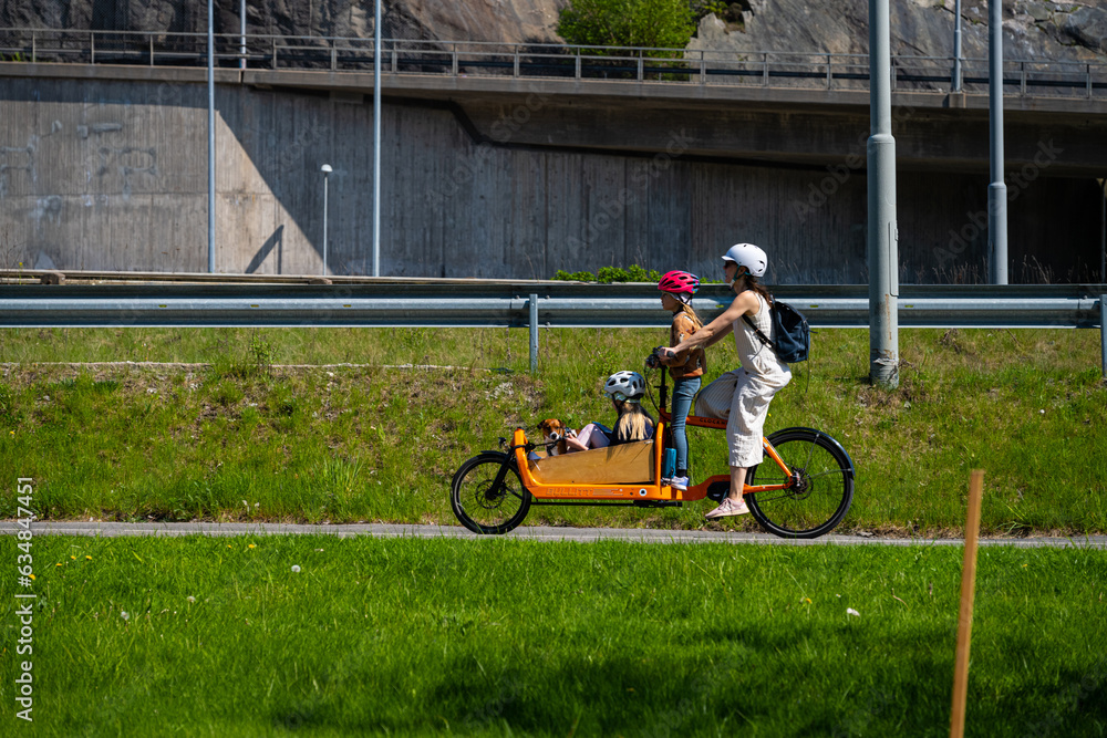 Obraz premium Family travelling on a yellow cargo electric assisted bicycle.