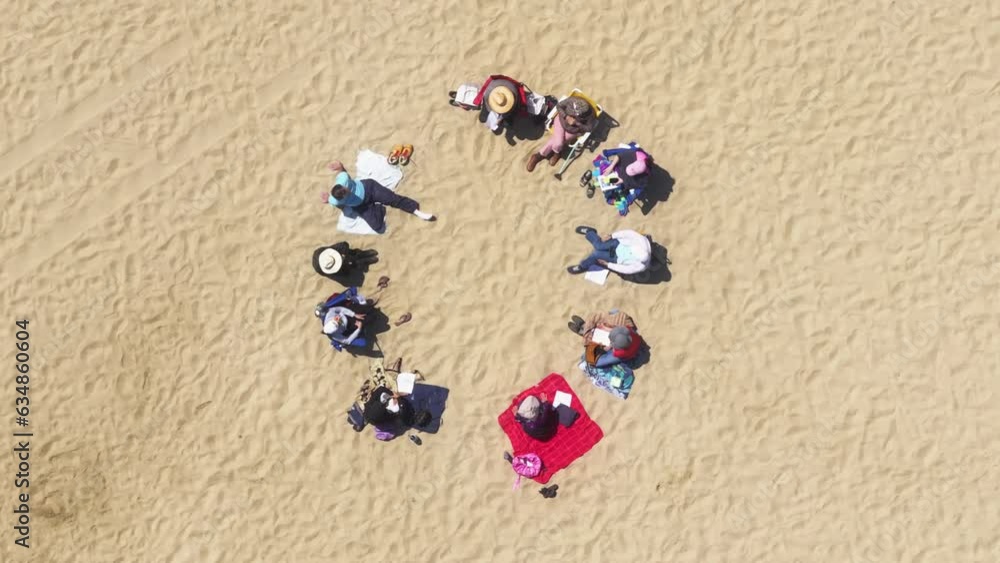 Top view of friends sitting on the beach, Santa Monica, Los Angeles, California, USA. Group of people talking together outdoors. Overhead shot of women and men relaxing on the sandy shore, 4k footage Top view of friends sitting on the beach, Santa Monica, Los Angeles, California, USA. Group of people talking together outdoors. Overhead shot of women and men relaxing on the sandy shore, 4k footage