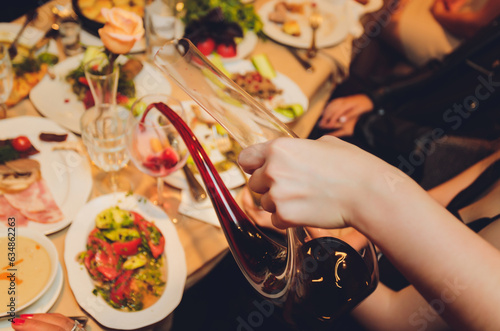 Sommelier pouring wine into glass from mixing bowl at luxury diner. photo