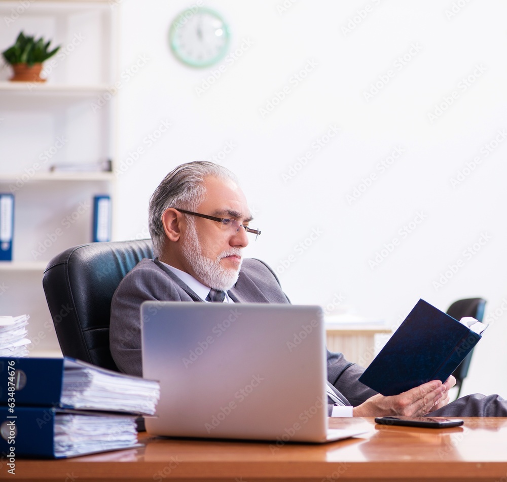 Old male businessman employee reading guidelines in the office Old male businessman employee reading guidelines in the office
