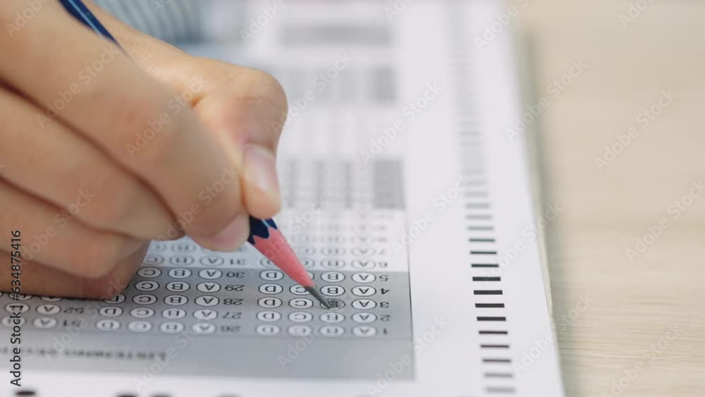 University students in uniform in classroom,Selective focus of the teenage college students sit on lecture chairs do final examination and write on examination paper answer sheets in the classroom. University students in uniform in classroom,Selective focus of the teenage college students sit on lecture chairs do final examination and write on examination paper answer sheets in the classroom.