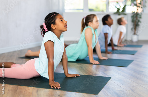 Preteen Children practicing yoga in Urdhva Mukha Shvanasana in the gym