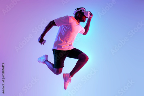 african american athletic man quickly runs and jumps in virtual reality glasses in neon lighting