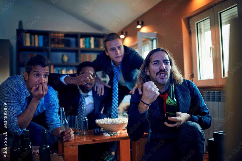 Young group of men watching a football game after work in a living room on the tv