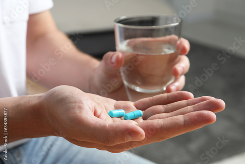Man with glass of water and pills on blurred background, closeup © New Africa