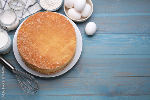 Canvas Print Plate with delicious sponge cake and ingredients on light blue wooden table, flat lay