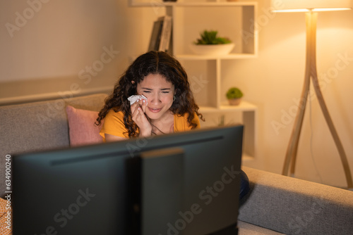 Young woman crying watching a movie on TV in the living room