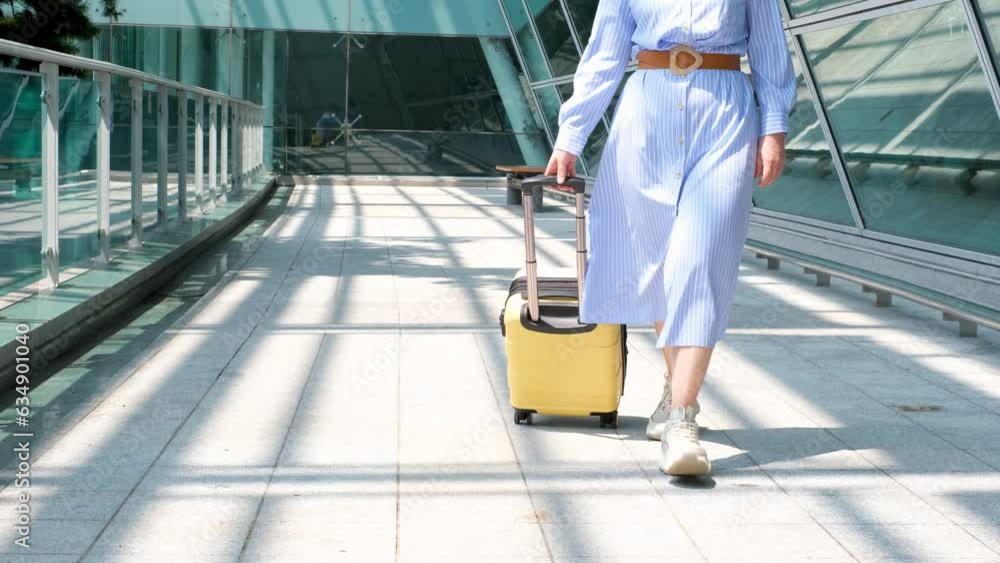 Young woman rolls yellow suitcase near the airport, travel concept. Young woman rolls yellow suitcase near the airport, travel concept.