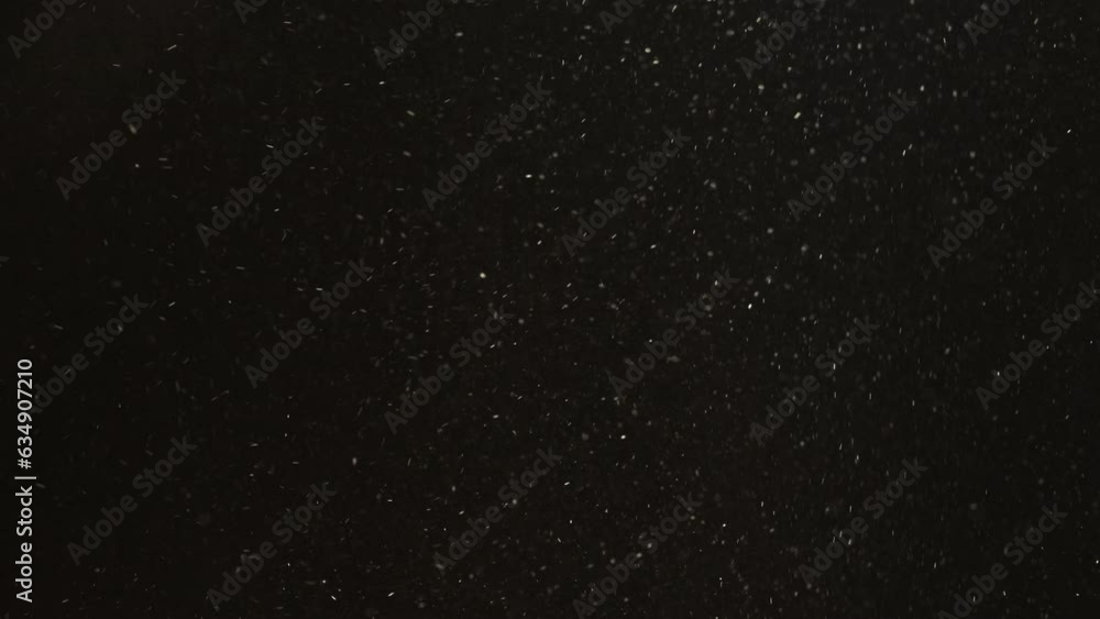Dust particles motion. Grain texture. Snow flakes. Defocused white powder flying floating on dark black abstract free space background. Dust particles motion. Grain texture. Snow flakes. Defocused white powder flying floating on dark black abstract free space background.