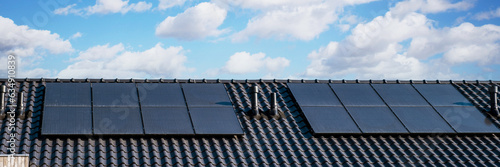 solar panels attached on the roof against a sunny sky Close up of new building with black solar panels. Zonnepanelen, Zonne energie, Translation: Solar panel, , Sun Energy photo