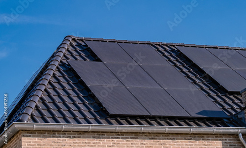 Black solar panels attached on the roof against a sunny sky Close up of new building with black solar panels. Zonnepanelen, Zonne energie, Translation: Solar panel, , Sun Energy