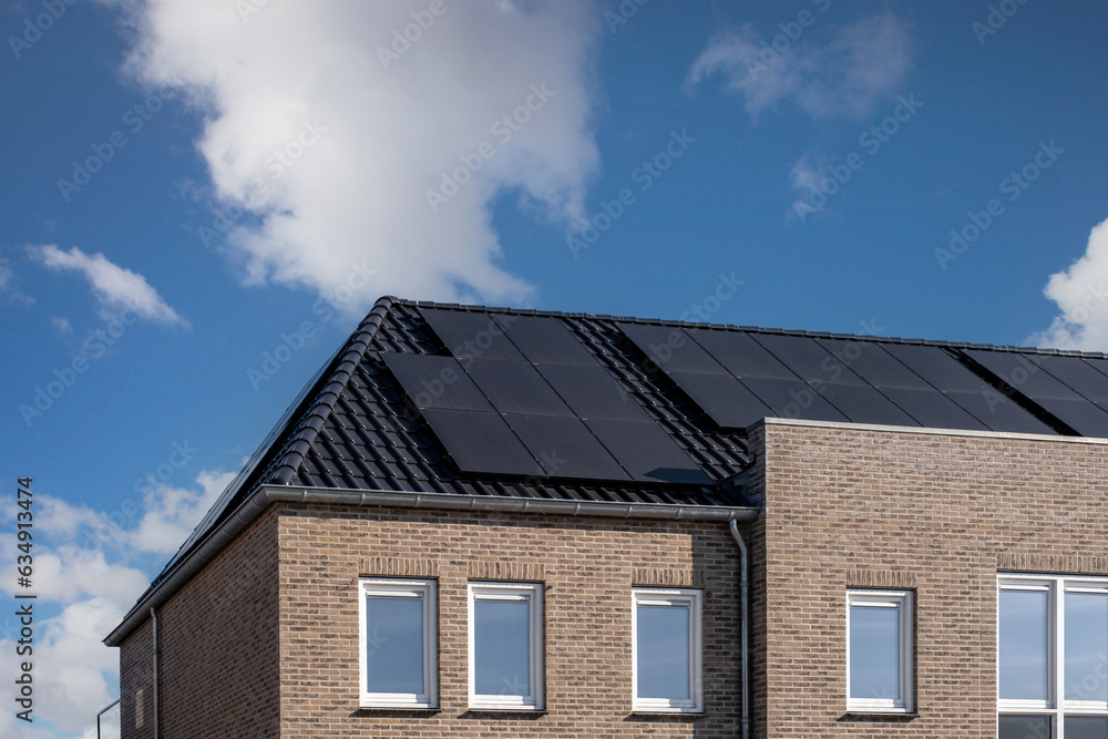 Newly build houses with solar panels attached on the roof against a sunny sky in the Netherlands