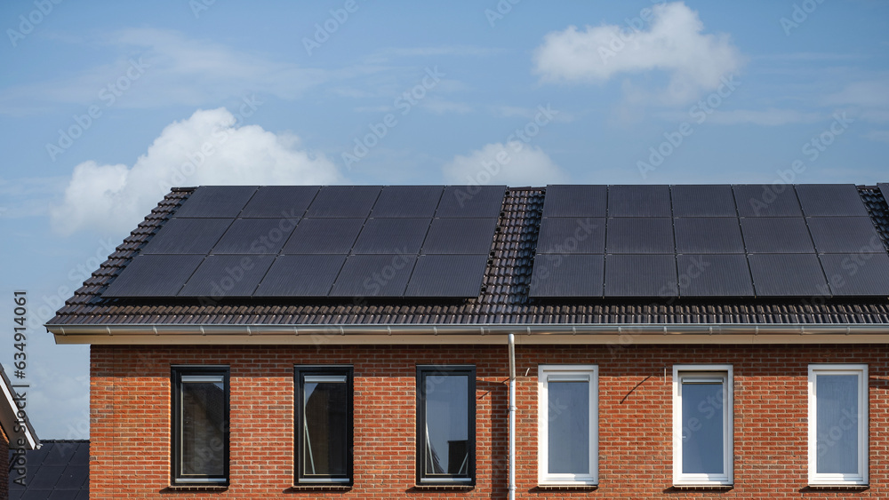 Newly build houses with solar panels attached on the roof against a sunny sky in the Netherlands