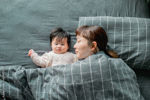 春の日中、布団で顔をくっつけてお昼寝するアジア人の母親と赤ちゃんの親子 photo