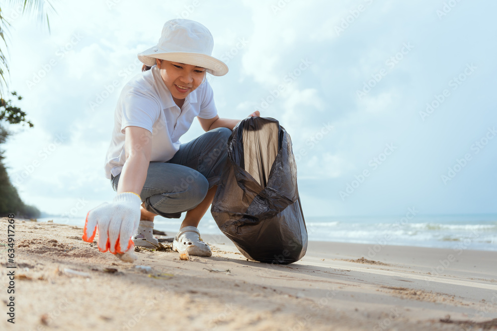 Asian young woman Cleaning and collecting trash on the beach