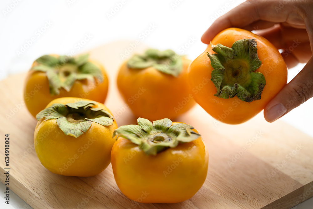 Fresh persimmon fruit with hand in autumn season Fresh persimmon fruit with hand in autumn season
