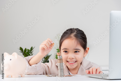 Asian little cute girl wearing a cream suit analyzing coins finance and investment