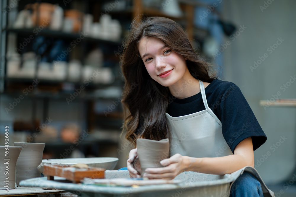 Crafting magic in her studio, a young woman engages in pottery work, carefully scraping to evolve the form. Crafting magic in her studio, a young woman engages in pottery work, carefully scraping to evolve the form.