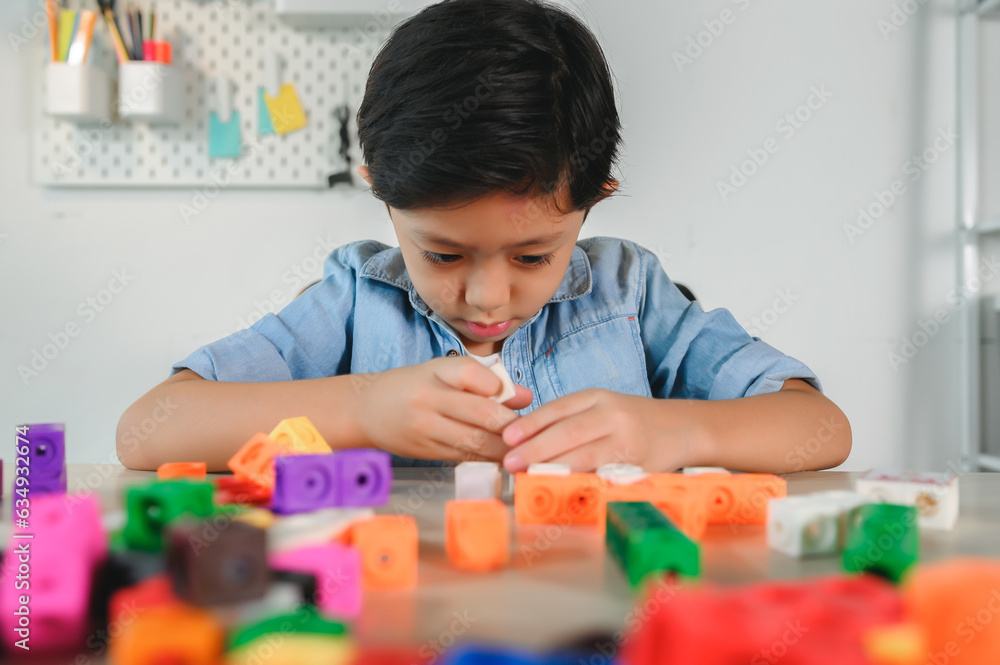 Asian Young Child Playing Colorful Plastic Cubes on Desk at Home. Learning and Education on Counting Cube in Math, Develop the Brain and Meditation while Playing. Asian Young Child Playing Colorful Plastic Cubes on Desk at Home. Learning and Education on Counting Cube in Math, Develop the Brain and Meditation while Playing.
