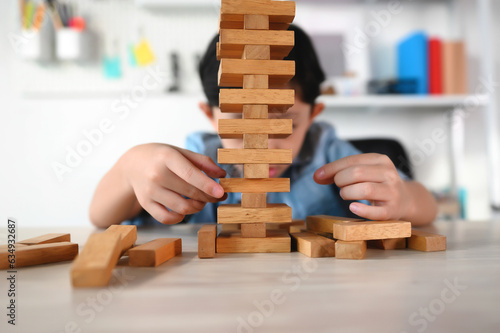 Child Boy Playing Jenga Game Exciting on Desk at Home. Unleashing Fun and Skill. Careful and Attentive Keeping, Concentrate and Slowly Take It Out while Playing. Study and learn to balance objects.