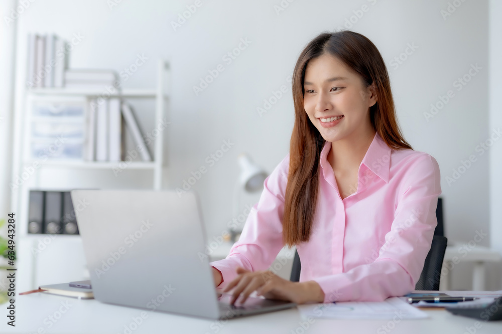 Successful Asian businesswoman smiling using laptop computer at office. Confident Asia businesswoman sitting happily in the office. Successful Asian businesswoman smiling using laptop computer at office. Confident Asia businesswoman sitting happily in the office.