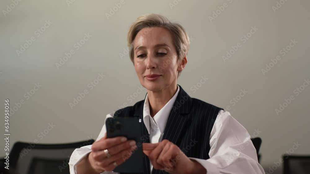 Closeup portrait of tired middle-aged business woman using mobile phone indoors, feeling discomfort from dry irritated eyes. Senior adult female suffering from blurry vision eyestrain problem. Closeup portrait of tired middle-aged business woman using mobile phone indoors, feeling discomfort from dry irritated eyes. Senior adult female suffering from blurry vision eyestrain problem.