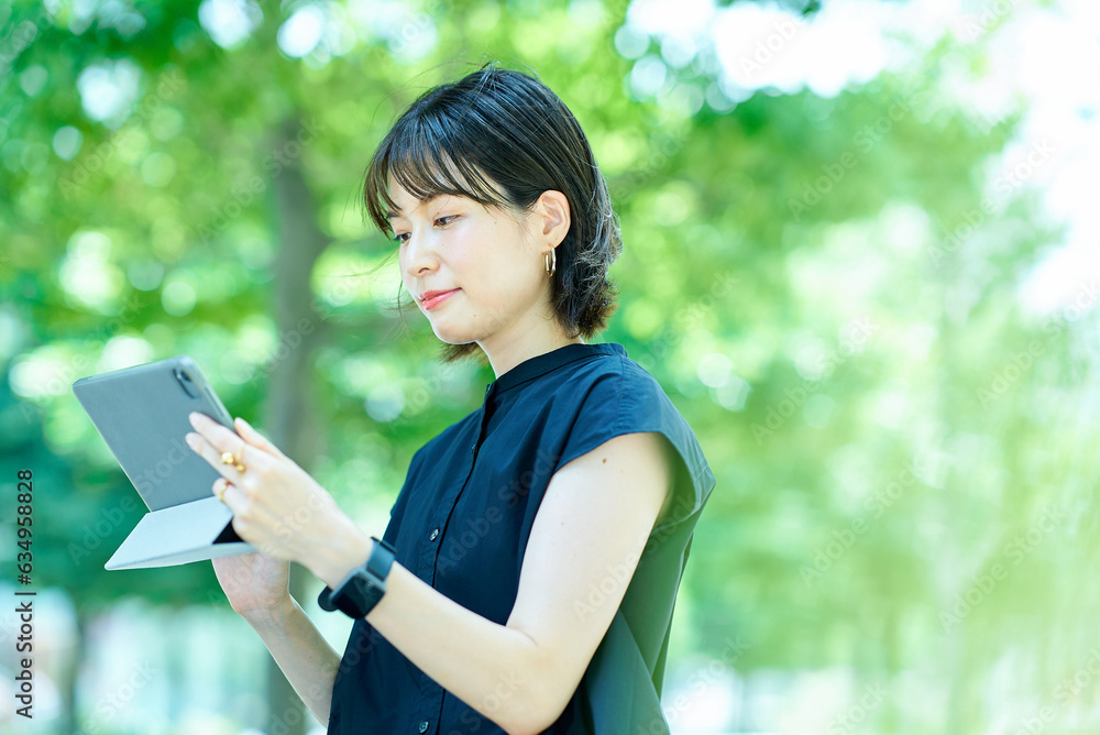 Fototapeta premium 屋外でタブレットPCを操作する若い女性