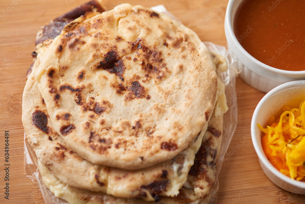 Central America traditional pupusas, a flavorful delight from El Salvador, Honduras, and Nicaragua, served with curtido and sauce on a rustic wooden tray Central America traditional pupusas, a flavorful delight from El Salvador, Honduras, and Nicaragua, served with curtido and sauce on a rustic wooden tray