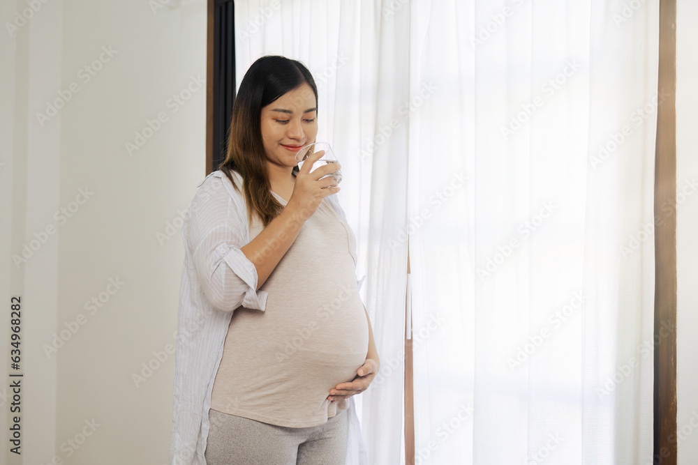 pregnancy woman hugging her tummy and feel happy with big belly at window