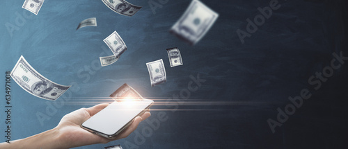 Fotografi Online earnings concept with woman hand holding cellphone and US dollar banknote