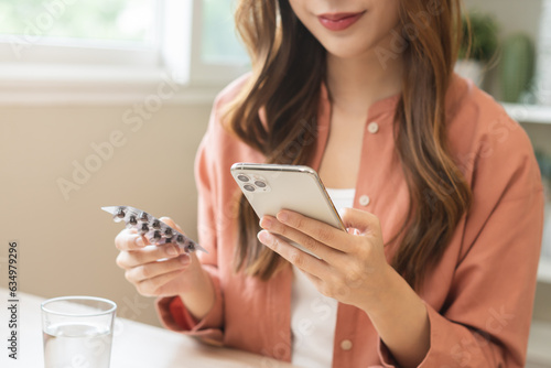 Health care asian young woman using smart mobile for reading, searching prescription medicine, pills label text about medical information online, instructions side effects, pharmacy medicament concept photo