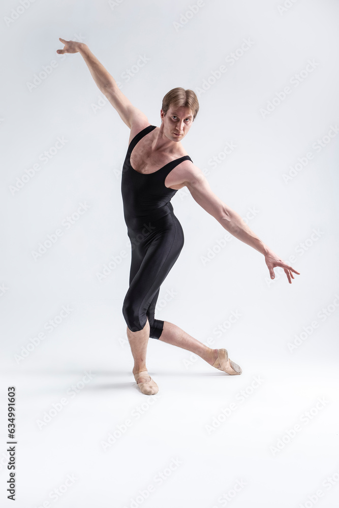 Fototapeta premium Sports Concepts and Ideas. Young Athletic Caucasian Ballet Dancer Man Posing in Stretching Pose With Hands Lifted in Line and Knees Bended in Black Tights On White.